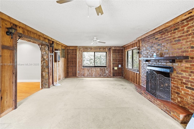 4878 NW 2nd Ct, Plantation, FL 33317 - unfurnished living room with a ceiling fan, wooden walls, a textured ceiling, a fireplace, and baseboards