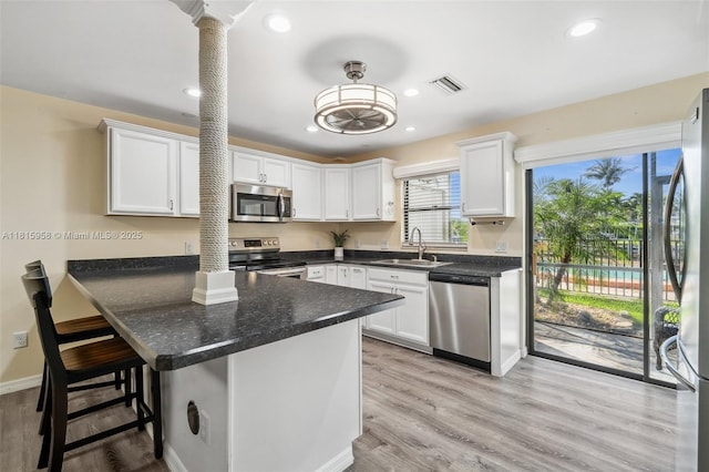 4803 SW Santa Barbara Ct Unit 5, Cape Coral, FL 33914 - kitchen with stainless steel appliances, decorative columns, white cabinetry, recessed lighting, and a kitchen breakfast bar