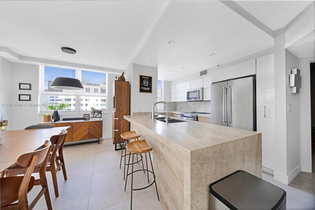 1155 Brickell Bay Dr Unit 3002, Miami, FL 33131 - kitchen featuring stainless steel appliances, modern cabinets, a kitchen bar, light tile patterned flooring, and light countertops