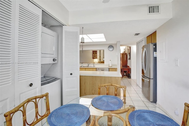 9510 Seagrape Dr Unit 101, Davie, FL 33324 - kitchen featuring appliances with stainless steel finishes, stacked washing machine and dryer, a sink, a skylight, and light tile patterned floors