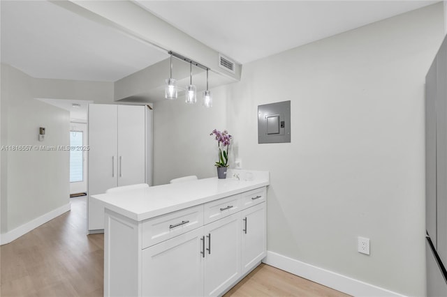 9091 Lime Bay Blvd Unit 211, Tamarac, FL 33321 - kitchen featuring electric panel, a peninsula, baseboards, and light wood-type flooring