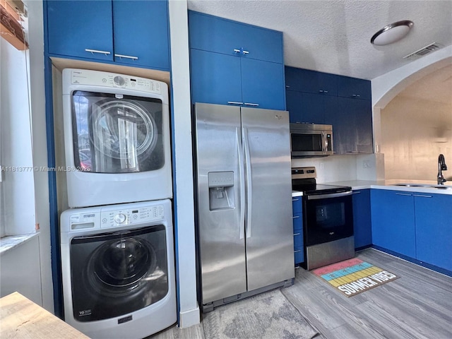 120 SW 109th Ave Unit 3, Sweetwater, FL 33174 - laundry area with stacked washer and clothes dryer, arched walkways, light wood-style flooring, and a textured ceiling