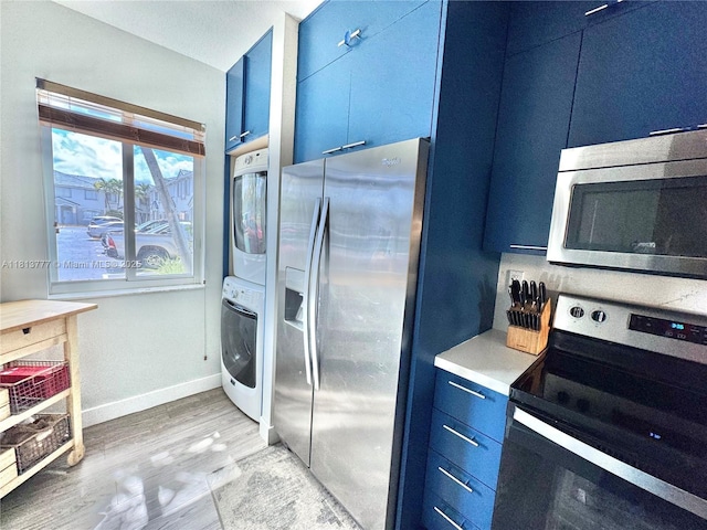 120 SW 109th Ave Unit 3, Sweetwater, FL 33174 - kitchen with stainless steel appliances, estacked washer and dryer, blue cabinetry, and light wood finished floors