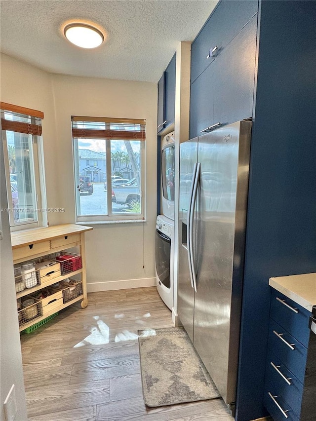 120 SW 109th Ave Unit 3, Sweetwater, FL 33174 - kitchen with stainless steel fridge, blue cabinets, stacked washer and clothes dryer, a textured ceiling, and light wood finished floors