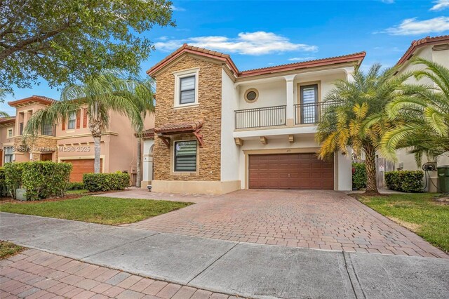 628 SE 37th Pl, Homestead, FL 33033 - mediterranean / spanish house with a balcony, stucco siding, decorative driveway, an attached garage, and stone siding