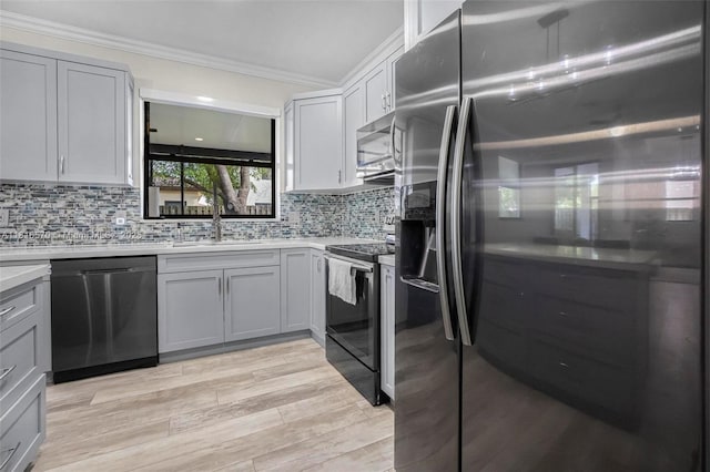 628 SE 37th Pl, Homestead, FL 33033 - kitchen with stainless steel appliances, ornamental molding, a sink, decorative backsplash, and light wood-style flooring