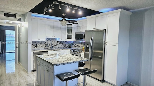 1401 SW 134th Way Unit 412C, Pembroke Pines, FL 33027 - kitchen featuring appliances with stainless steel finishes, a textured ceiling, decorative backsplash, ceiling fan, and a center island