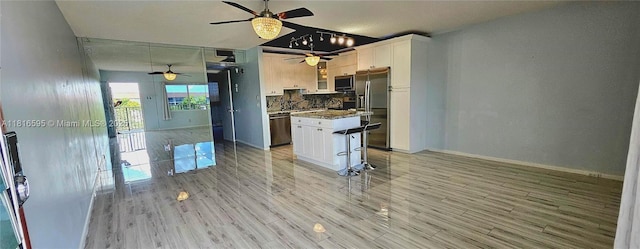 1401 SW 134th Way Unit 412C, Pembroke Pines, FL 33027 - kitchen with appliances with stainless steel finishes, ceiling fan, white cabinets, a center island, and tasteful backsplash