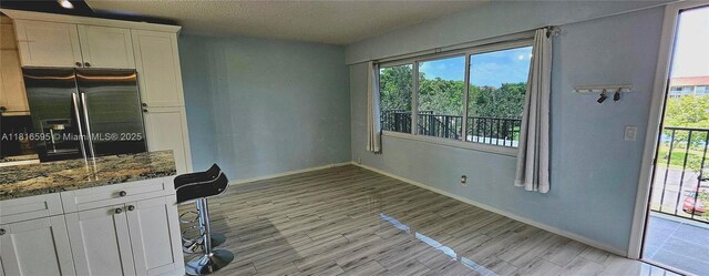 1401 SW 134th Way Unit 412C, Pembroke Pines, FL 33027 - kitchen featuring fridge with ice dispenser, white cabinets, dark stone counters, a textured ceiling, and light wood-style flooring