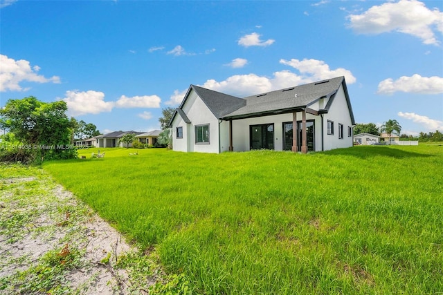 4308 3rd St SW, Lehigh Acres, FL 33976 - rear view of house featuring stucco siding, a shingled roof, and a yard
