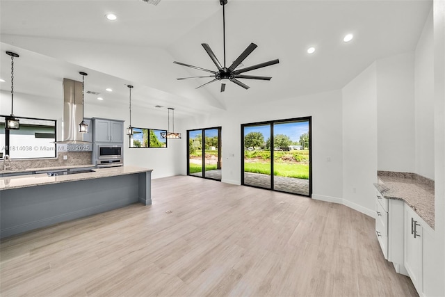4308 3rd St SW, Lehigh Acres, FL 33976 - kitchen featuring island exhaust hood, built in microwave, light stone countertops, vaulted ceiling, and oven