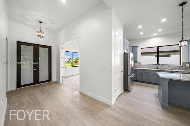 4308 3rd St SW, Lehigh Acres, FL 33976 - kitchen with freestanding refrigerator, light stone countertops, light wood-type flooring, decorative light fixtures, and recessed lighting