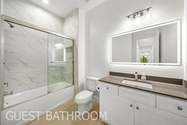 4308 3rd St SW, Lehigh Acres, FL 33976 - full bathroom with wood finished floors, vanity, toilet, bath / shower combo with glass door, and baseboards