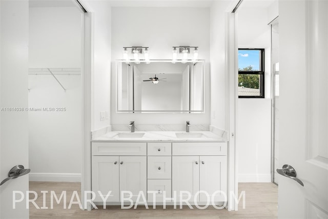 4308 3rd St SW, Lehigh Acres, FL 33976 - bathroom with baseboards, double vanity, and wood finished floors