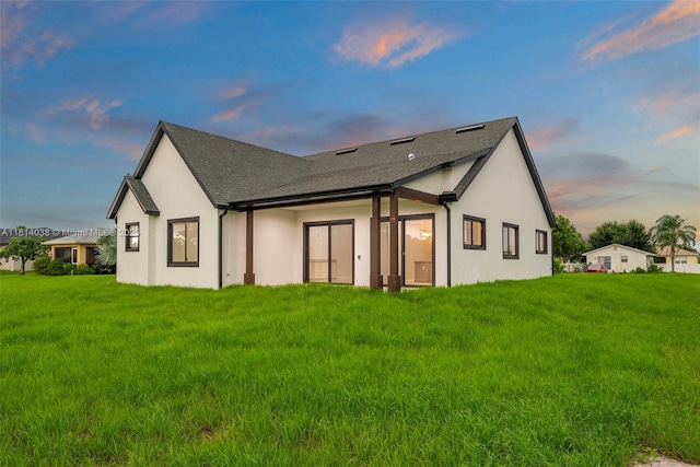 4308 3rd St SW, Lehigh Acres, FL 33976 - back of property at dusk featuring stucco siding, a yard, and a shingled roof