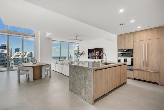 92 SW 3rd St Unit 5204, Miami, FL 33130 - kitchen featuring light brown cabinets, a sink, modern cabinets, light stone countertops, and an island with sink