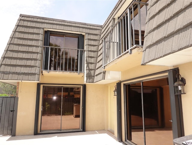 4226 42nd Way, West Palm Beach, FL 33407 - entrance to property featuring stucco siding, a balcony, and mansard roof