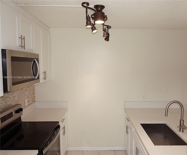 4226 42nd Way, West Palm Beach, FL 33407 - kitchen with stainless steel appliances, a sink, white cabinets, decorative backsplash, and a textured ceiling