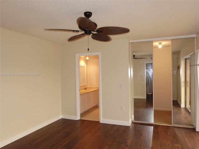 4226 42nd Way, West Palm Beach, FL 33407 - unfurnished bedroom featuring wood finished floors, a textured ceiling, ensuite bathroom, baseboards, and ceiling fan