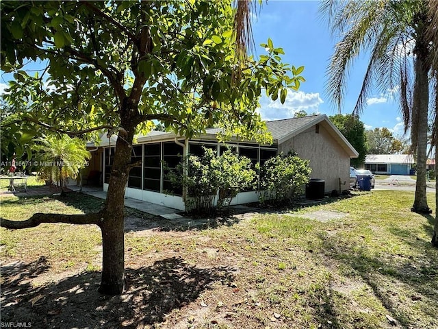 2016 Mariner Ct, La Belle, FL 33935 - view of property exterior featuring a sunroom, a lawn, central AC unit, and stucco siding