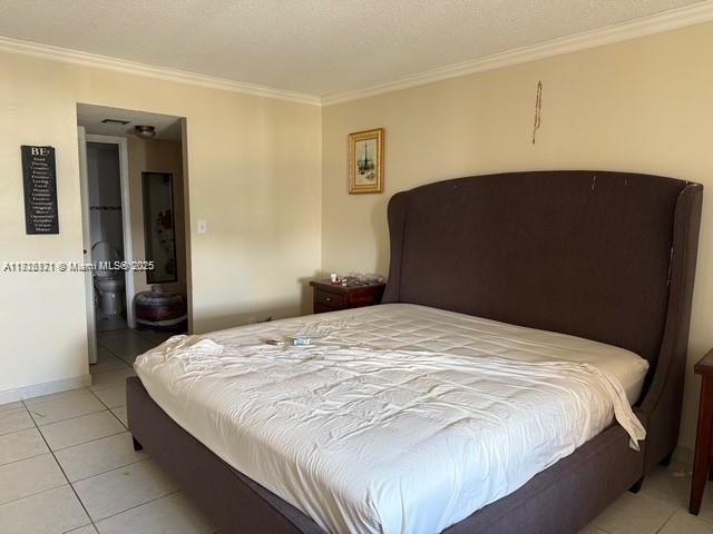 2025 NE 164th St Unit 414, North Miami Beach, FL 33162 - bedroom featuring ornamental molding, light tile patterned floors, and baseboards