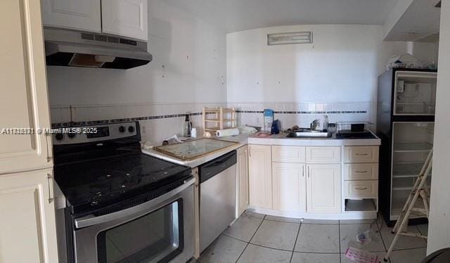 2025 NE 164th St Unit 414, North Miami Beach, FL 33162 - kitchen with appliances with stainless steel finishes, under cabinet range hood, light tile patterned floors, white cabinets, and light countertops
