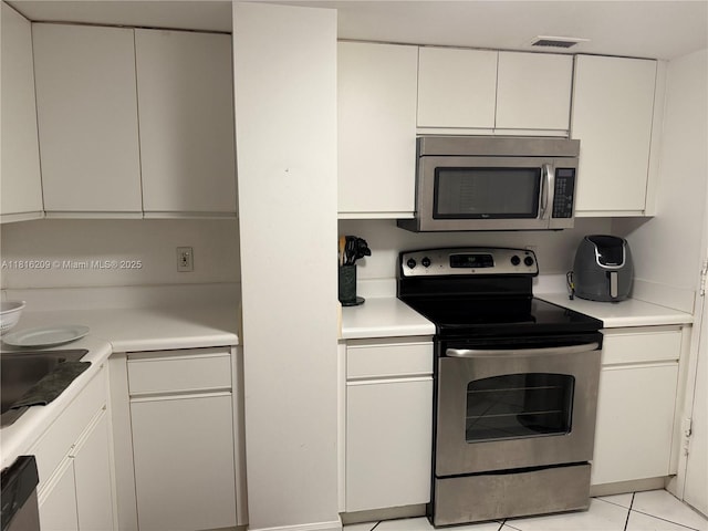 5161 Collins Ave Unit 216, Miami Beach, FL 33140 - kitchen with appliances with stainless steel finishes, light countertops, and white cabinetry