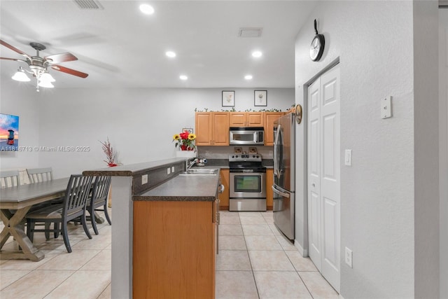 14063 SW 49th Ct Unit 4, Miramar, FL 33027 - kitchen featuring stainless steel appliances, a peninsula, dark countertops, a ceiling fan, and light tile patterned flooring