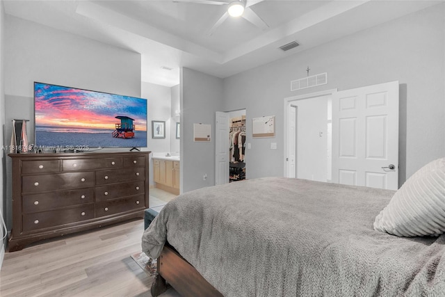 14063 SW 49th Ct Unit 4, Miramar, FL 33027 - bedroom with light wood-type flooring, a tray ceiling, a walk in closet, ensuite bathroom, and a ceiling fan