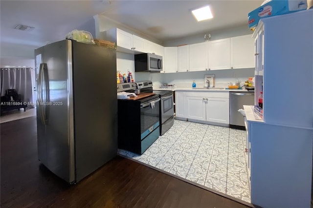 1109 S M St, Lake Worth, FL 33460 - kitchen featuring appliances with stainless steel finishes, a sink, light countertops, white cabinetry, and light wood finished floors