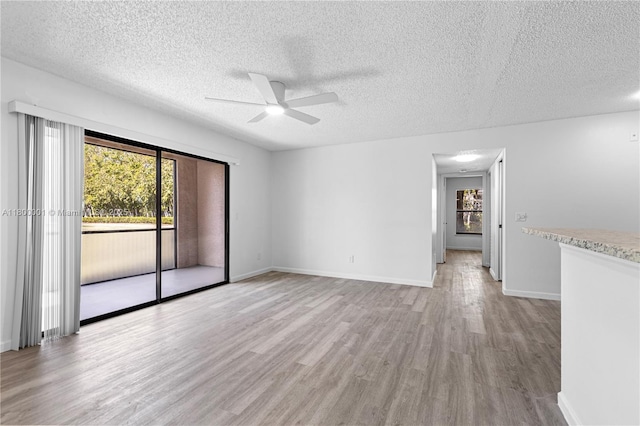 2094 Arbour Walk Unit 318, Naples, FL 34109 - spare room with healthy amount of natural light, light wood-style floors, a textured ceiling, a ceiling fan, and baseboards