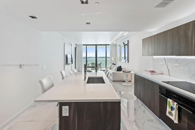 3131 NE 7th Ave Unit 1702, Miami, FL 33137 - kitchen with black appliances, light marble finish flooring, modern cabinets, light countertops, and floor to ceiling windows