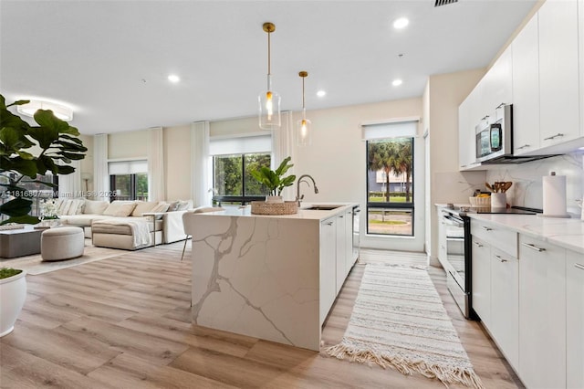 8001 NW 41st St Unit F-107, Doral, FL 33166 - kitchen with a sink, electric stove, light wood-type flooring, stainless steel microwave, and an island with sink
