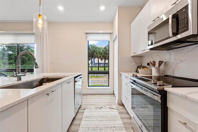 8001 NW 41st St Unit F-107, Doral, FL 33166 - kitchen featuring appliances with stainless steel finishes, a sink, white cabinetry, tasteful backsplash, and light stone counters