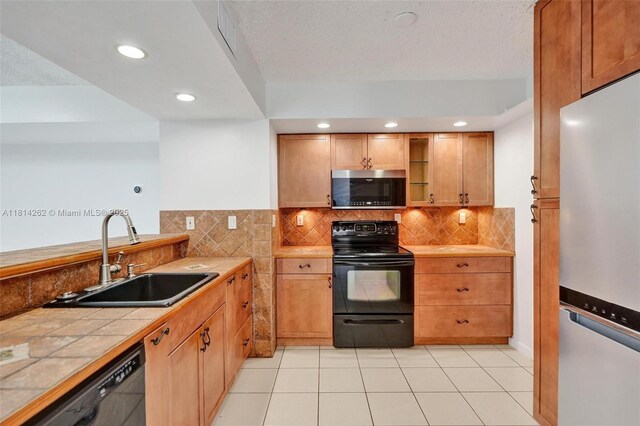 2388 NW 97th Way, Pembroke Pines, FL 33024 - kitchen with black appliances, tile countertops, decorative backsplash, light tile patterned floors, and recessed lighting