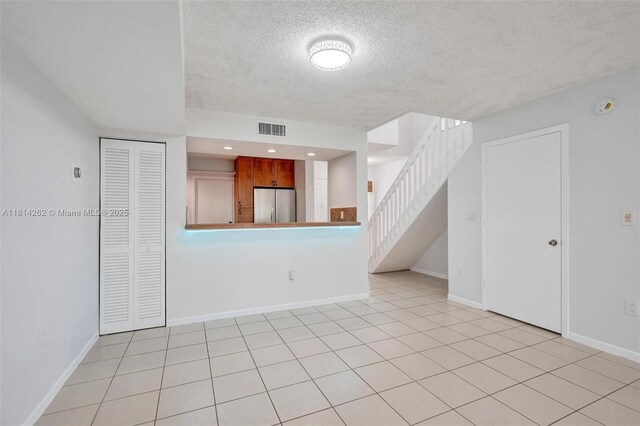 2388 NW 97th Way, Pembroke Pines, FL 33024 - unfurnished living room featuring a textured ceiling, stairs, and light tile patterned floors