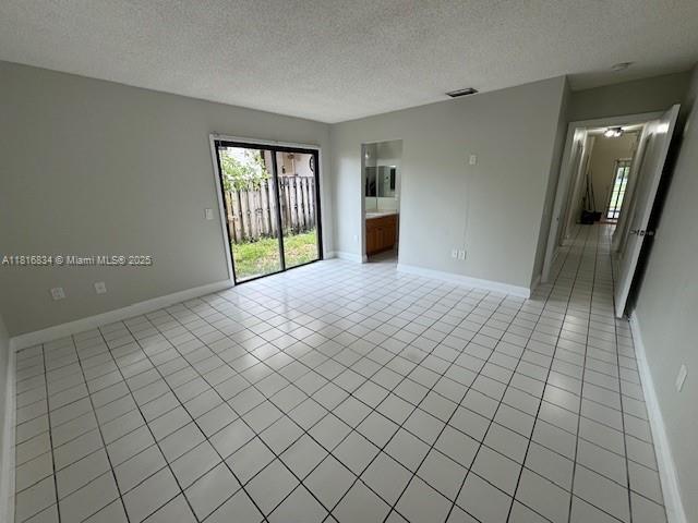 10626 SW 148th Ave Dr, Miami, FL 33196 - unfurnished room featuring light tile patterned floors, a textured ceiling, and baseboards
