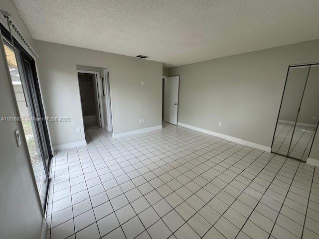 10626 SW 148th Ave Dr, Miami, FL 33196 - unfurnished bedroom with multiple windows, a textured ceiling, baseboards, and light tile patterned floors