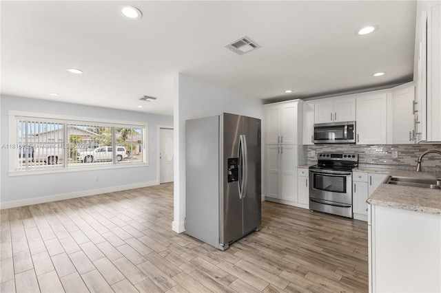 1023 N F St, Lake Worth, FL 33460 - kitchen featuring appliances with stainless steel finishes, a sink, tasteful backsplash, white cabinets, and baseboards