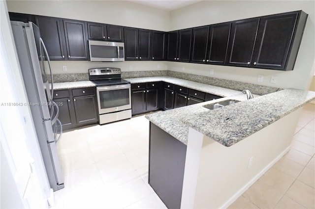 9120 SW 227th Ter, Cutler Bay, FL 33190 - kitchen with appliances with stainless steel finishes, a peninsula, light stone countertops, light tile patterned floors, and dark cabinetry