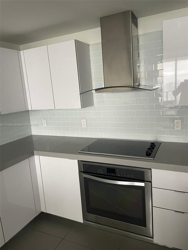 1600 NE 1st Ave Unit 3319, Miami, FL 33132 - kitchen featuring oven, black electric stovetop, wall chimney range hood, white cabinets, and tasteful backsplash