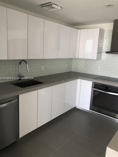 1600 NE 1st Ave Unit 3319, Miami, FL 33132 - kitchen featuring stainless steel appliances, wall chimney exhaust hood, a sink, and white cabinetry
