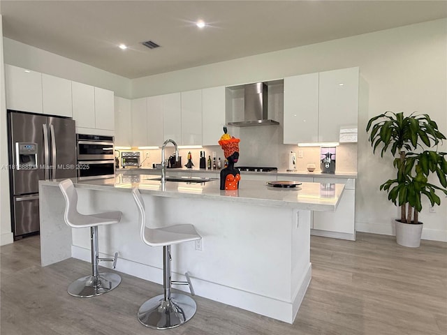 8167 NW 45th St, Doral, FL 33166 - kitchen with appliances with stainless steel finishes, wall chimney exhaust hood, a sink, modern cabinets, and light wood finished floors