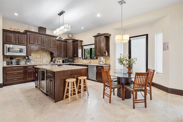 18825 N Bay Rd, Sunny Isles Beach, FL 33160 - kitchen featuring appliances with stainless steel finishes, dark brown cabinetry, a center island, tasteful backsplash, and beverage cooler