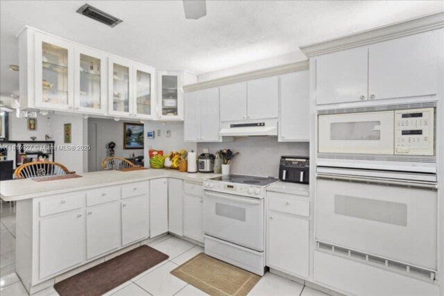 400 NW 41st Ave, Coconut Creek, FL 33066 - kitchen with white appliances, under cabinet range hood, a peninsula, and light countertops