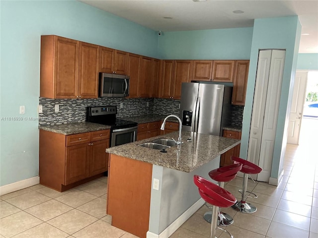 5220 NW 48th Ln, Tamarac, FL 33319 - kitchen with stainless steel appliances, brown cabinets, light tile patterned flooring, and backsplash