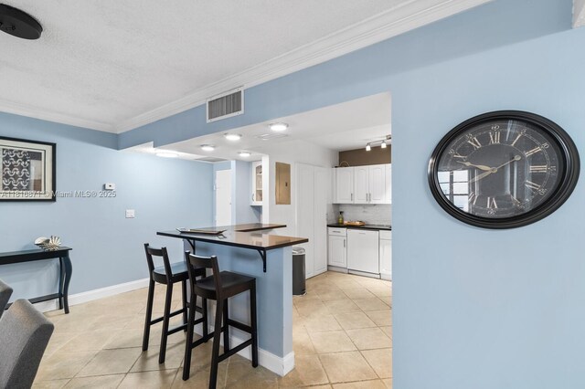 3725 S Ocean Dr Unit 1224, Hollywood, FL 33019 - kitchen featuring crown molding, dark countertops, light tile patterned floors, a breakfast bar, and white cabinetry