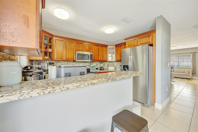 14521 SW 29th Ter Unit 14521, Miami, FL 33175 - kitchen with appliances with stainless steel finishes, light tile patterned floors, glass insert cabinets, tasteful backsplash, and brown cabinets