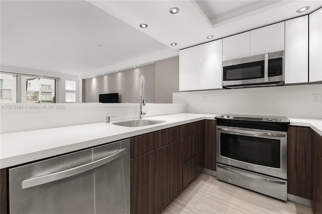 401 Ocean Dr Unit 221, Miami Beach, FL 33139 - kitchen featuring appliances with stainless steel finishes, a sink, light countertops, modern cabinets, and white cabinetry