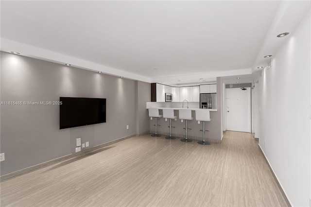 401 Ocean Dr Unit 221, Miami Beach, FL 33139 - unfurnished living room with recessed lighting, light wood finished floors, baseboards, and a sink